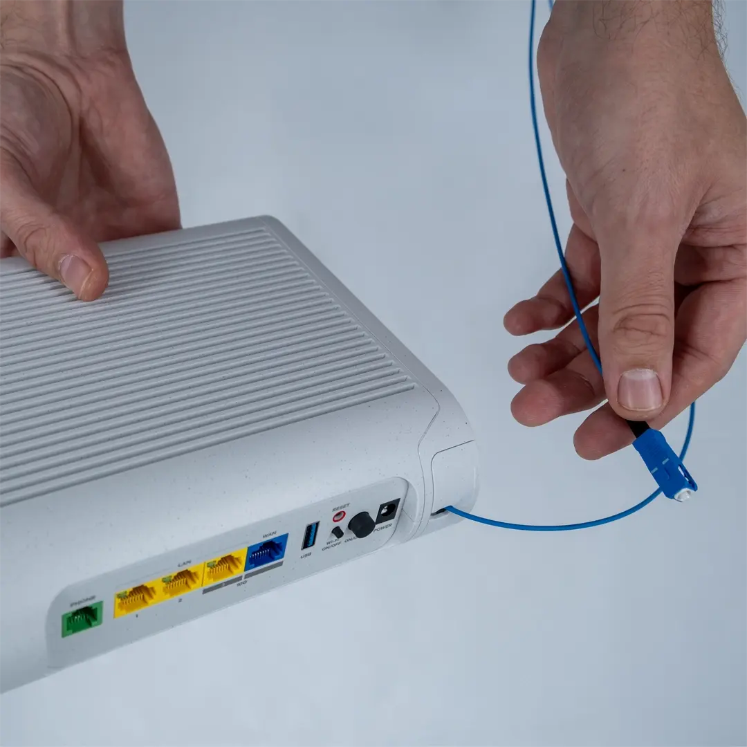 Eine Person hält den Router und zeigt die blaue Glasfaserkabel, die in die Glasfaserdose der Wohnung gesteckt werden soll.