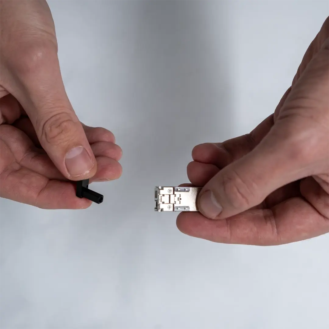 Eine Person hält ein SFP-Modul in der einen Hand und entfernt mit der anderen eine schwarze Schutzkappe.