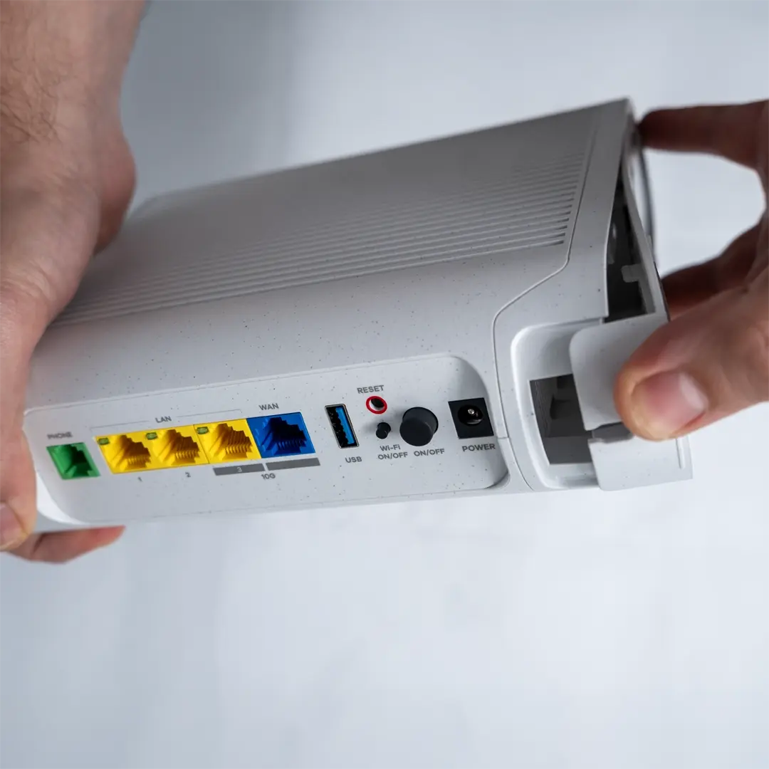 Eine Person löst vorsichtig die Bodenabdeckung des Routers, indem sie an der Kante zieht.